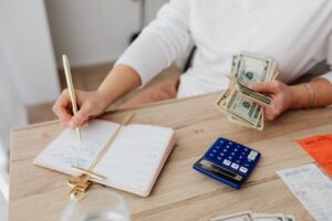 Bookkeeper holding money and recording expenses